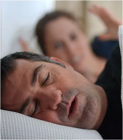 Man snoring with frustrated partner in the background