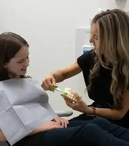 Dental Hygienist Demonstrating proper brushing technique to a young patient