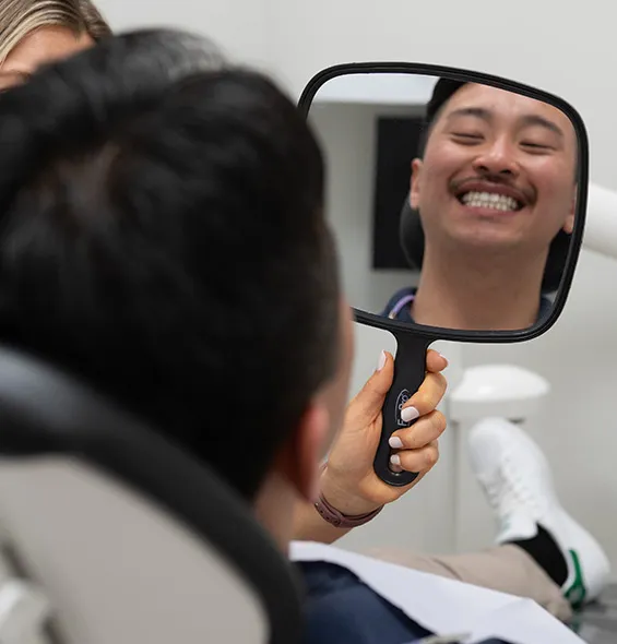 Patient smiling into mirror at dental office