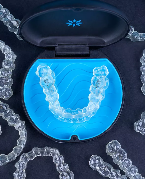 Close up of Invisalign clear aligners with one aligner in a blue Invisalign tray